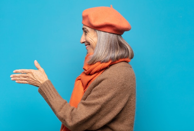 Mujer de mediana edad sonriendo, saludándote y ofreciendo un apretón de manos para cerrar un trato exitoso, concepto de cooperación