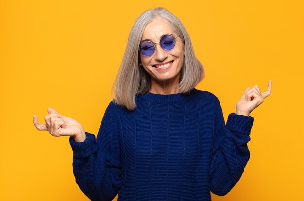 Mujer de mediana edad sonriendo, sintiéndose despreocupada, relajada y feliz, bailando y escuchando música, divirtiéndose en una fiesta