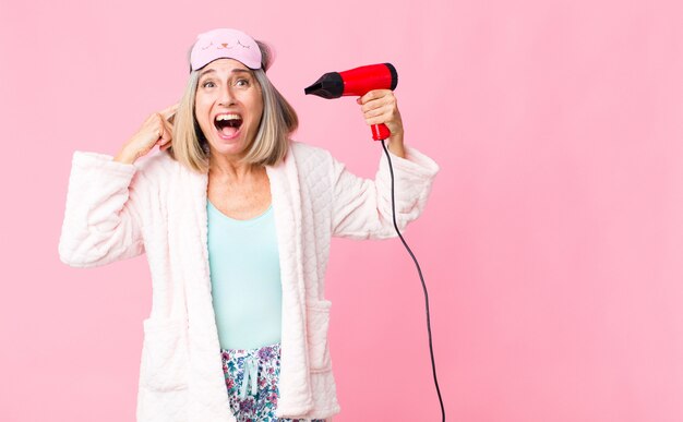 Mujer de mediana edad con traje de noche con secador de pelo