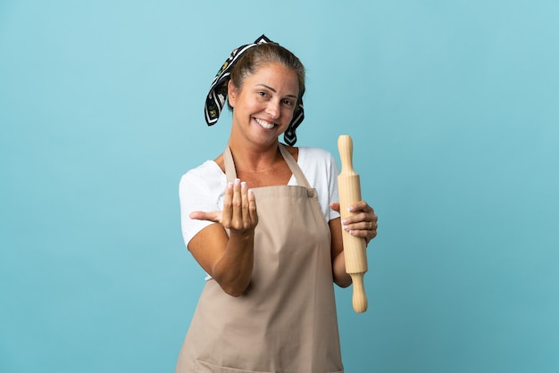 Mujer de mediana edad en uniforme de chef que invita a venir con la mano. Feliz de que hayas venido