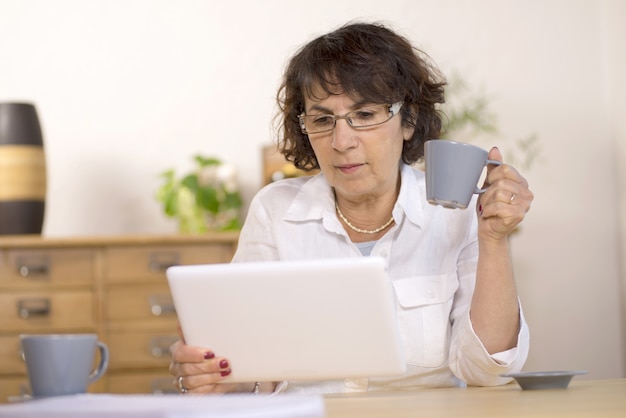 Una mujer de mediana edad usando una tableta de computadora