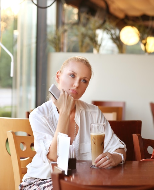 Mujer de mediana edad usando una tableta digital mientras está sentada en un café al aire libre