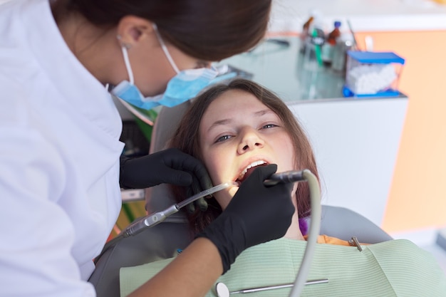 Mujer médico dentista tratar dientes a paciente mujer en consultorio dental