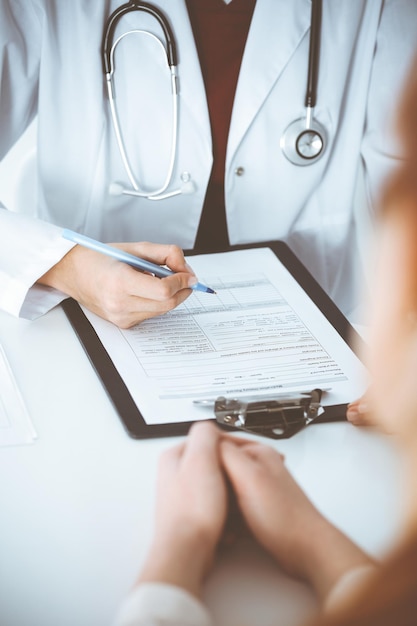 Mujer-médico desconocido que llena un formulario de solicitud mientras consulta al paciente. concepto de medicina.