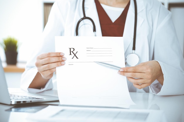 Foto mujer-médico desconocido que señala en el primer plano de registro de formulario de prescripción vacío. concepto de medicina.