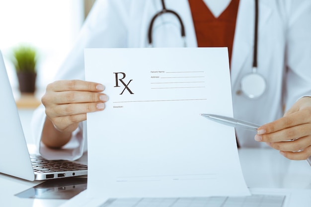 Mujer-médico desconocido que señala en el primer plano de registro de formulario de prescripción vacío. concepto de medicina.
