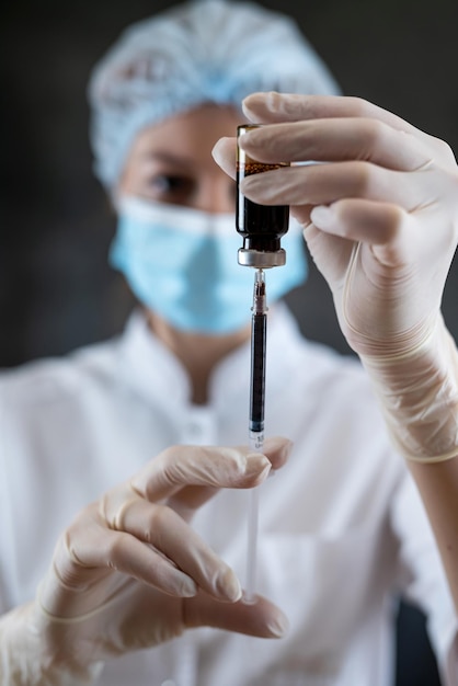 mujer médico en enfermera en uniforme médico completo preparar jeringa con medicamentos para la vacuna aislada