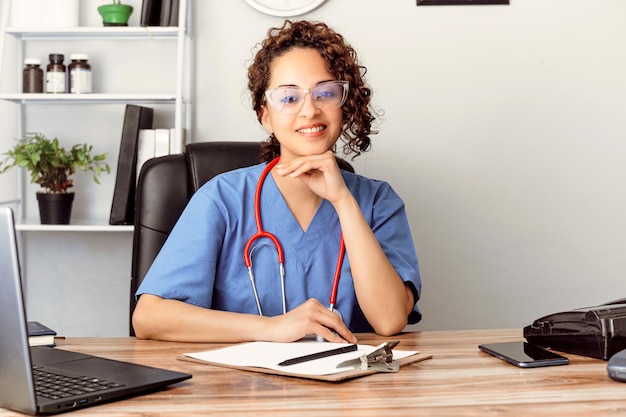 Foto mujer médico hispano con vista en la oficina de la clínica mirando a la cámara