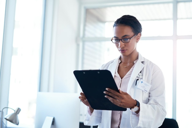 Mujer médico y lectura con clipboard para resultados médicos información o investigación en el hospital Persona femenina o empleada de atención médica chequeando documentos de papeleo o formularios de salud para el procedimiento