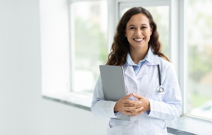 Mujer médico de pie junto a la ventana con una computadora portátil