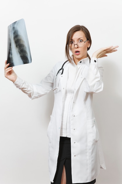 Mujer médico sorprendida mirando radiografía de pulmones, fluorografía, roentgen aislado sobre fondo blanco. Doctora en gafas de estetoscopio de bata médica. Personal sanitario, concepto de medicina. Neumonía.