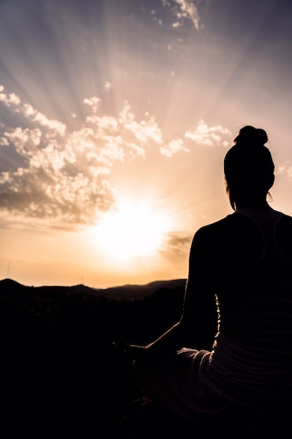 Foto mujer durante la meditación con la puesta de sol