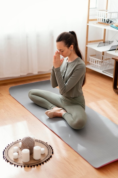 Foto mujer meditando en casa en mat