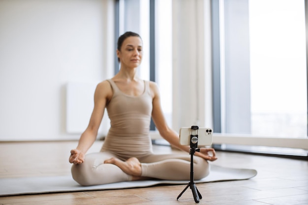 Mujer meditando y hablando a la cámara mientras está sentada en la postura del loto