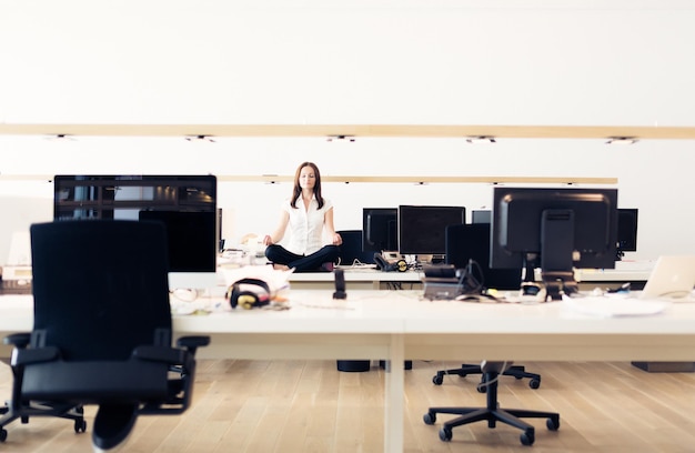 Mujer meditando en la mesa en la oficina