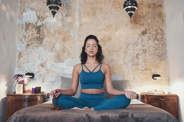 Foto mujer meditando mientras está sentada en la cama en casa