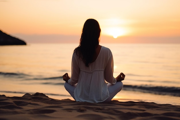 una mujer meditando en la playa frente al atardecer.