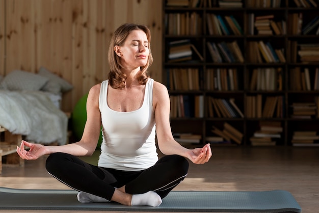 Foto mujer meditando sobre estera de yoga