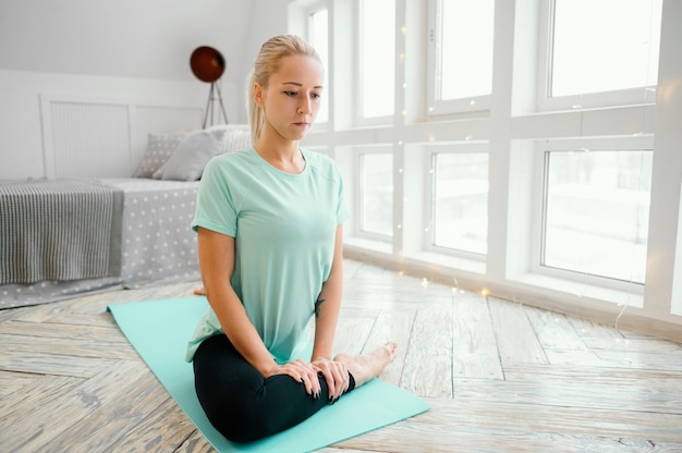 Foto mujer meditando sobre estera