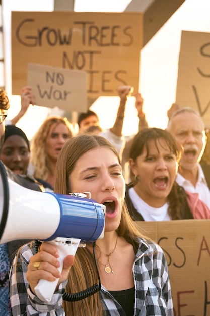 Mujer con megáfono en grupo de protesta activistas se manifiestan juntos gritando contra las guerras