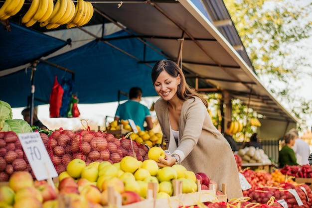 Mujer en el mercado, buscando frutas y verduras.