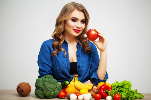 Mujer en una mesa con frutas y verduras