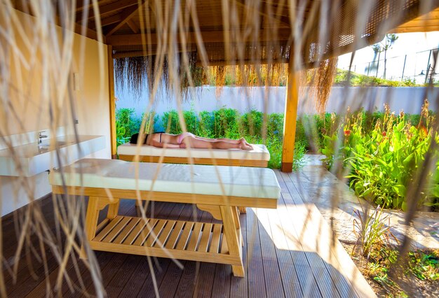 Mujer en la mesa de masajes. Salón de spa al aire libre