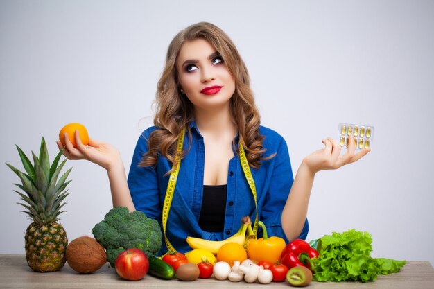 Mujer en la mesa con naranja y pastillas en frutas y verduras