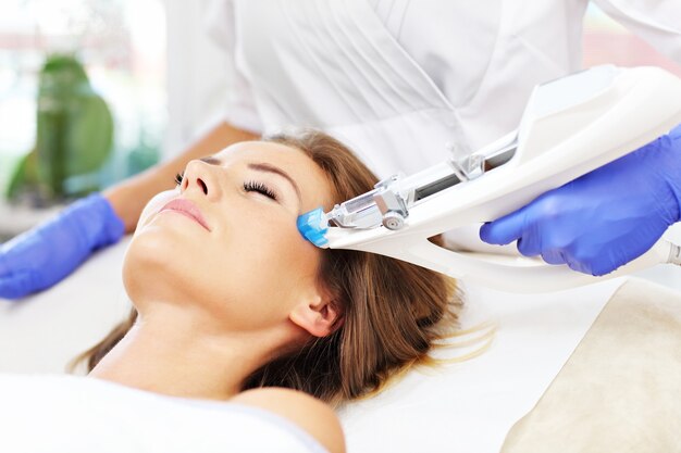 Mujer con mesoterapia facial en salón de belleza.