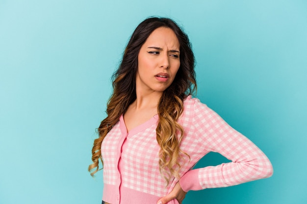 Mujer mexicana joven aislada en azul que sufre un dolor de espalda.