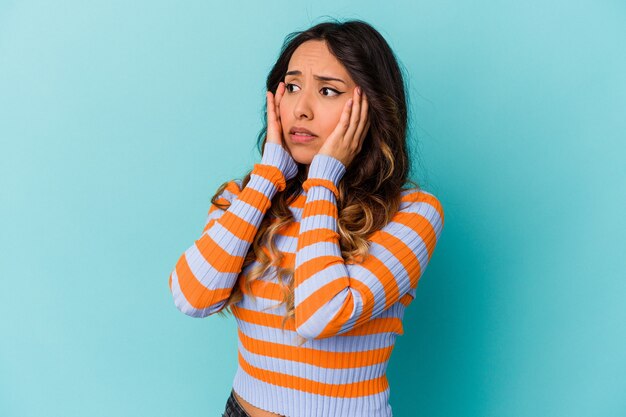 Mujer mexicana joven aislada en la pared azul asustada y asustada.