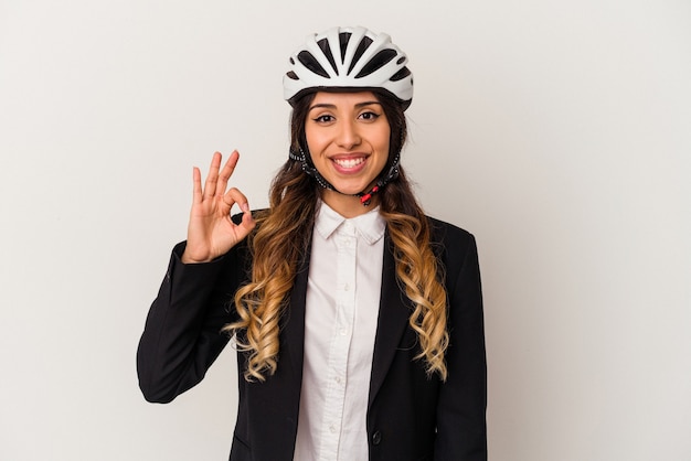 Mujer mexicana joven en bicicleta para trabajar aislado en la pared blanca alegre y confiado mostrando gesto ok.