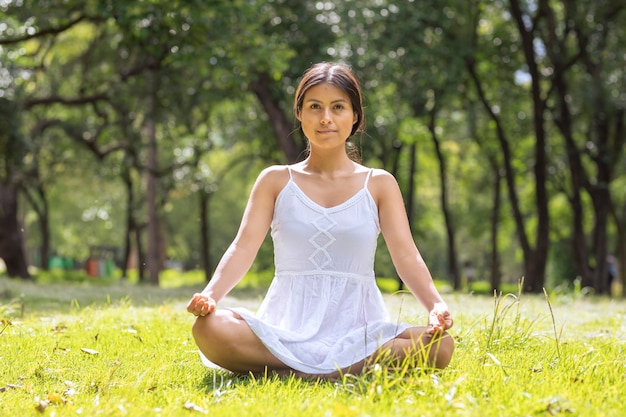 Mujer mexicana en posición de flor de loto meditando en el parque