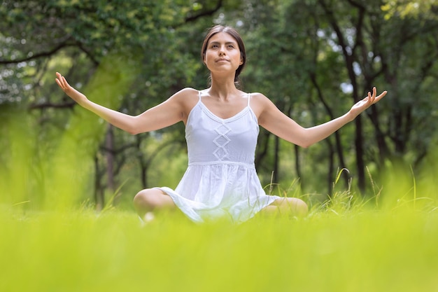 Mujer mexicana en posición de flor de loto meditando en el parque