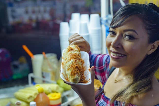Foto mujer mexicana preparando un maíz hervido comida típica de la calle mexicana puesto de comida elote