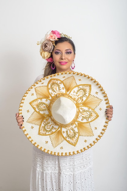 Mujer mexicana con tocado de flores sosteniendo un sombrero mariachi Mujer con sombrero de fondo blanco