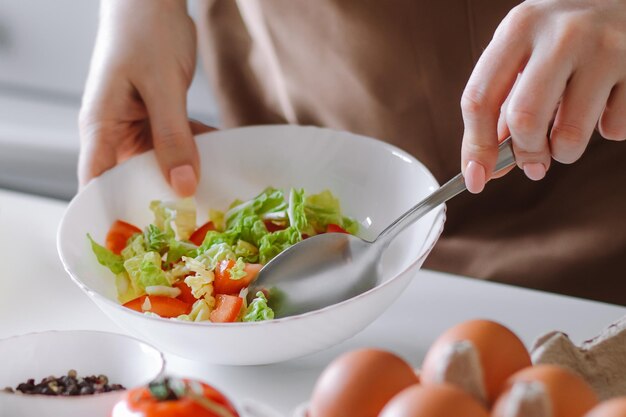 Mujer mezcla ensalada de verduras en un tazón Cocina casera para una dieta saludable