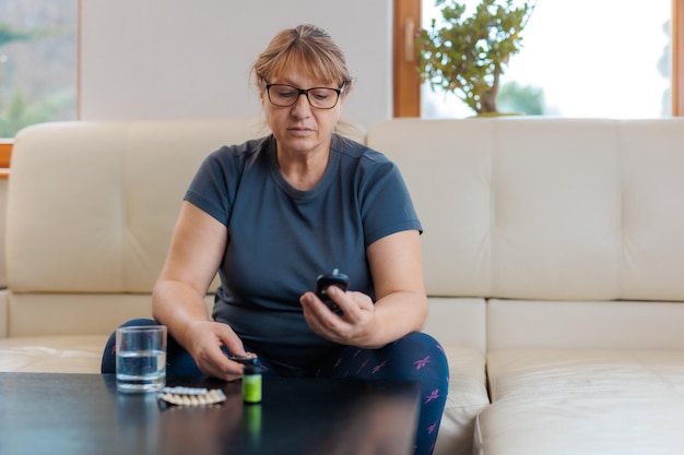 La mujer mide el azúcar en la sangre, el medidor de glucosa, el cuaderno del concepto de diabetes para escribir y monitorear La mujer escribe el nivel de glucosa en la sangre del medidor de glucosa, la consulta médica y el examen en el hospital