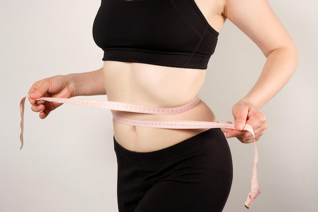 Una mujer mide la circunferencia del abdomen.