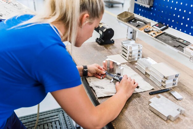 Mujer midiendo pieza de metal