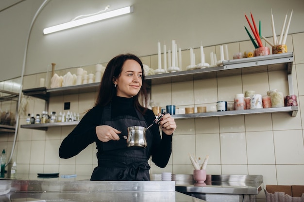 Mujer midiendo la temperatura de la cera derretida en el primer plano de la cocina Haciendo velas caseras