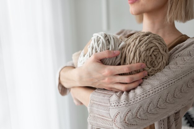 Mujer midiendo el trozo de la cuerda de la bobina para tejer macramé con grandes tijeras de sastre