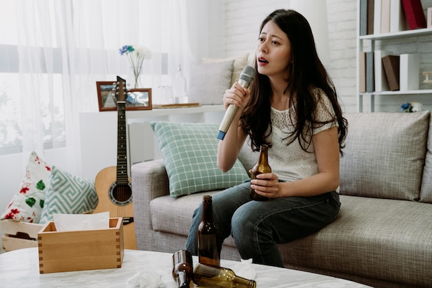 mujer milenaria asiática ahogando sus penas con cerveza y karaoke después de que su novio la dejó. una chica japonesa está llorando mientras las canciones tristes reviven dolorosos recuerdos de su ex.