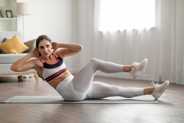 Mujer milenaria esbelta atlética haciendo ejercicio en la sala de estar