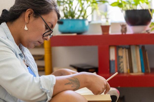 Mujer milenaria tatuada mexicana leyendo un libro