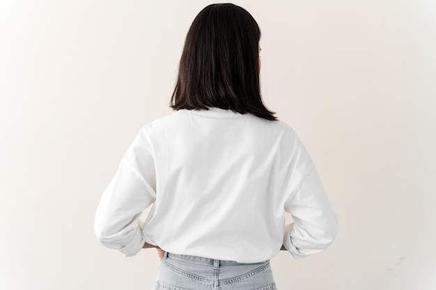 Mujer milenaria vistiendo camiseta blanca de pie volviendo a la cámara