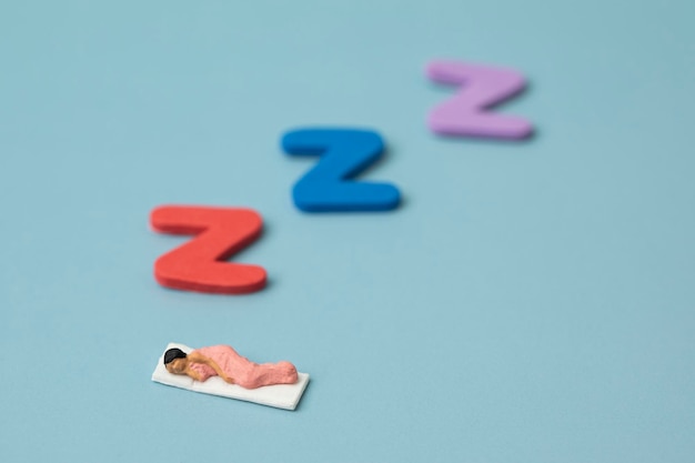 Foto mujer en miniatura durmiendo sobre fondo azul.