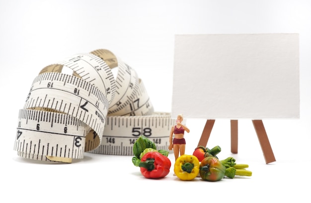 Mujer miniatura con verduras y cinta métrica