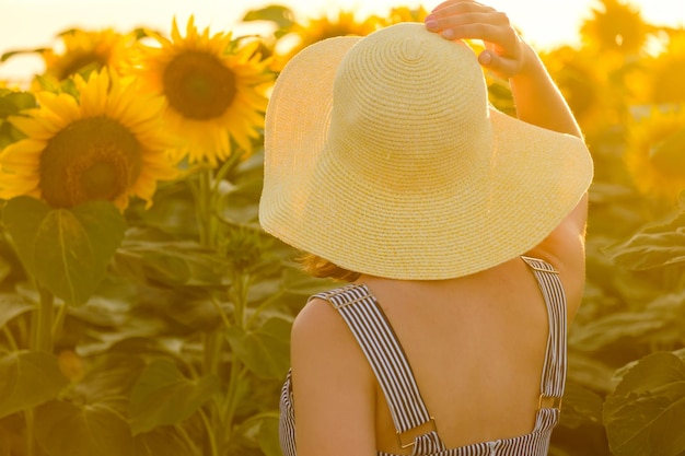 La mujer mira los girasoles brillantes que crecen en campo rural