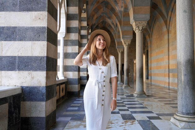 Foto mujer mira hacia el lado cuando camina en la colonnada fuera de la catedral de san andrés de amalfi, italia